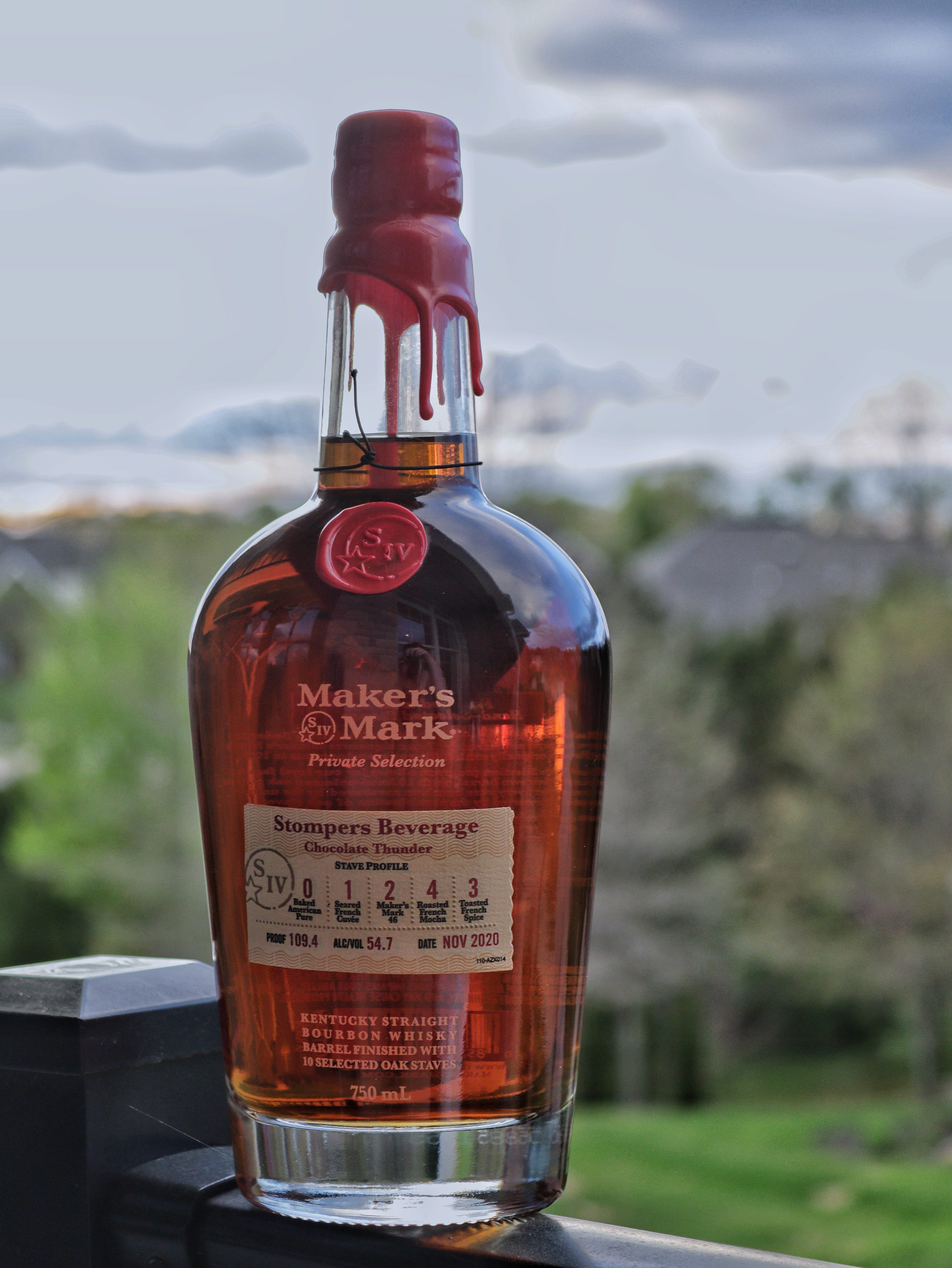 Maker's Mark Bourbon Bottle sitting on a rail over looking neighborhood