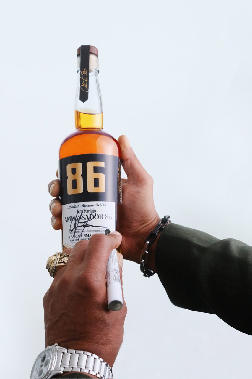 Antonio Freeman signing a bottle of Luca Mariano Ambassador 86 Bourbon.
