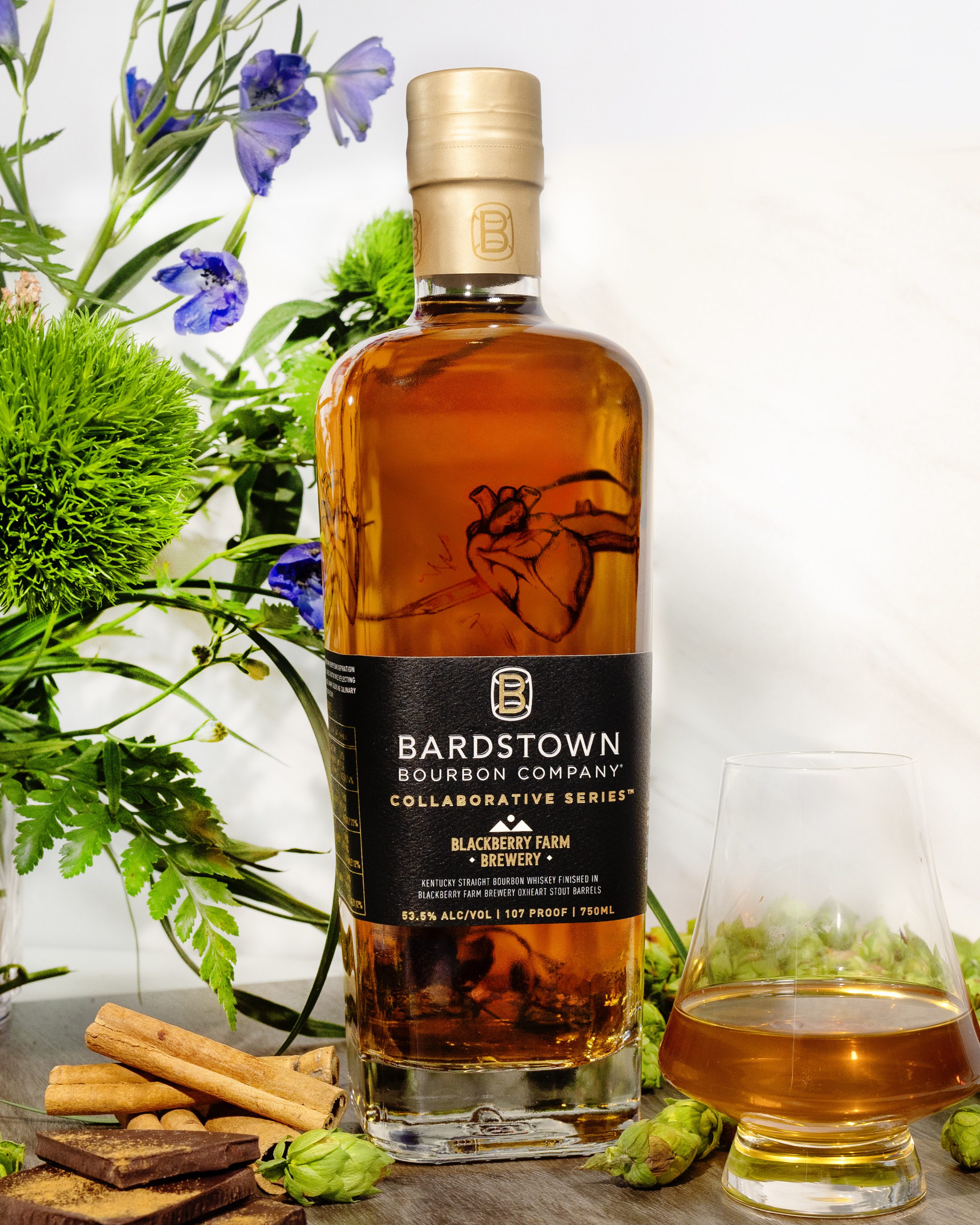 Bottle with glass, flowers and ingredients