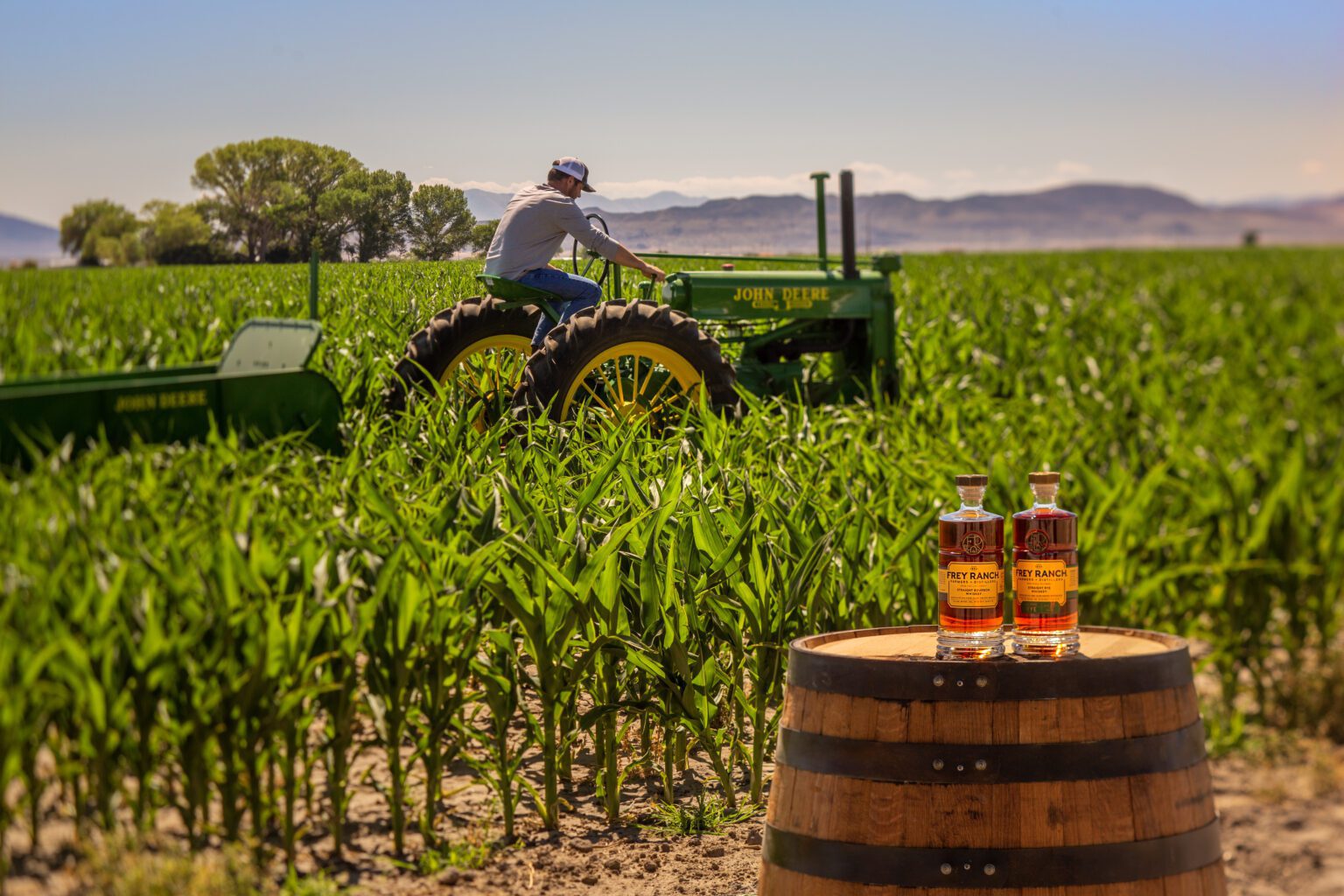 Colby Frey on A tractor in the field with two bottles of Frey Ranch