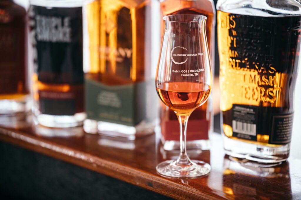 A glass with bottles behind it.
