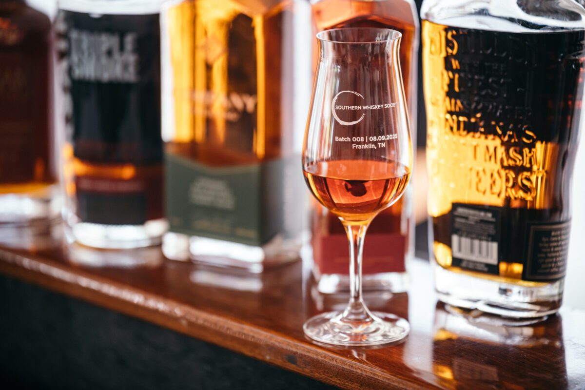 A glass with bottles behind it.